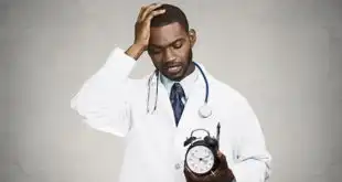 médico com uma mão na cabeça e um relógio na outra, sofrendo burnout