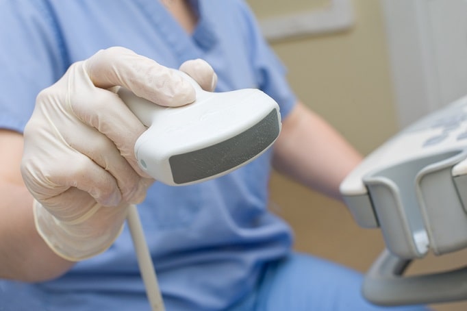 mão de médico com aparelho de ultrassom para realizar exame em paciente com coronavírus