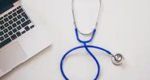 Médico do SUS equipado com laptop para teleatendimento de pacientes.
