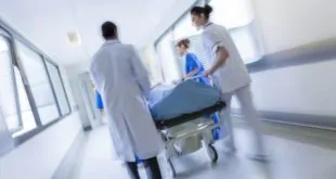 médicos levando paciente pós-PCR para cateterismo coronário
